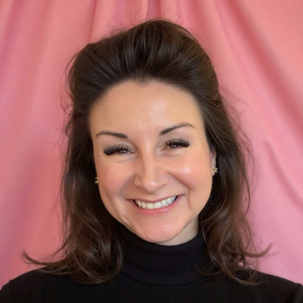 Portrait of Rochelle Hamiliton, founder of Rochelle H Consulting, wearing a black turtleneck in front of a pink draped background.